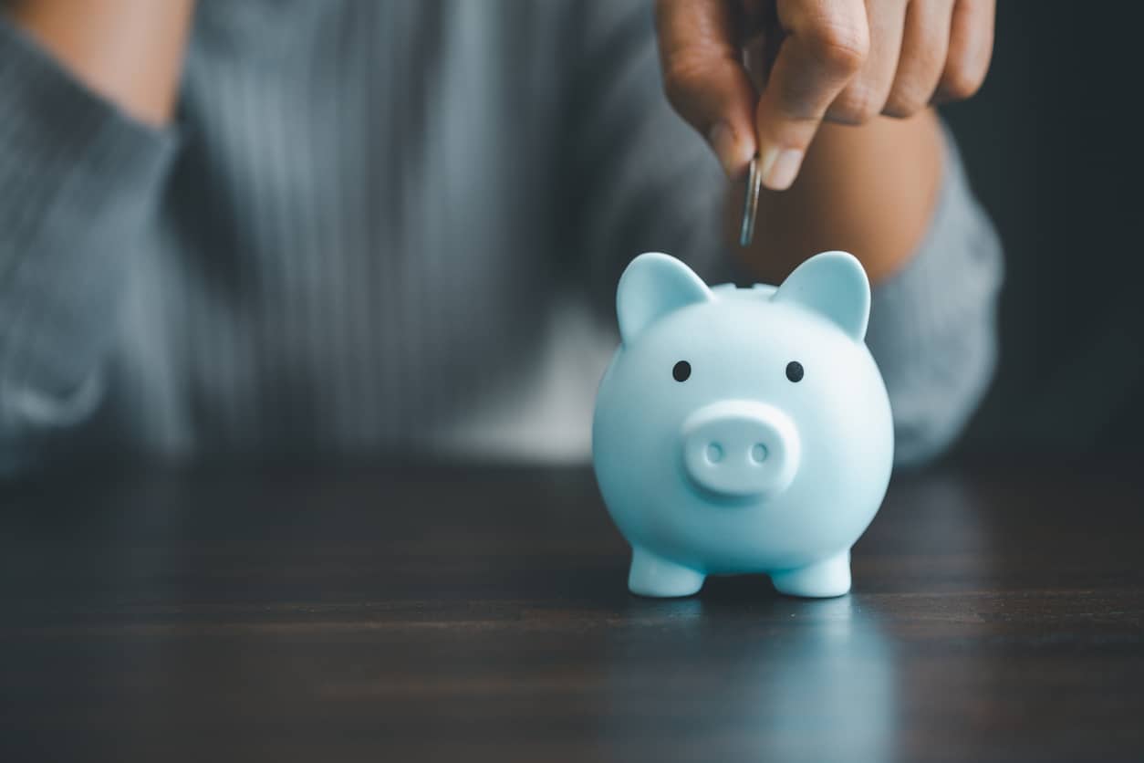 Dropping coins into a piggy bank